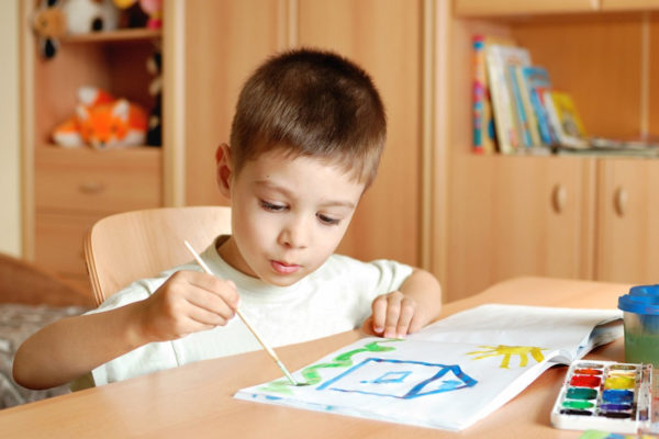 Мальчик рисует домик красками